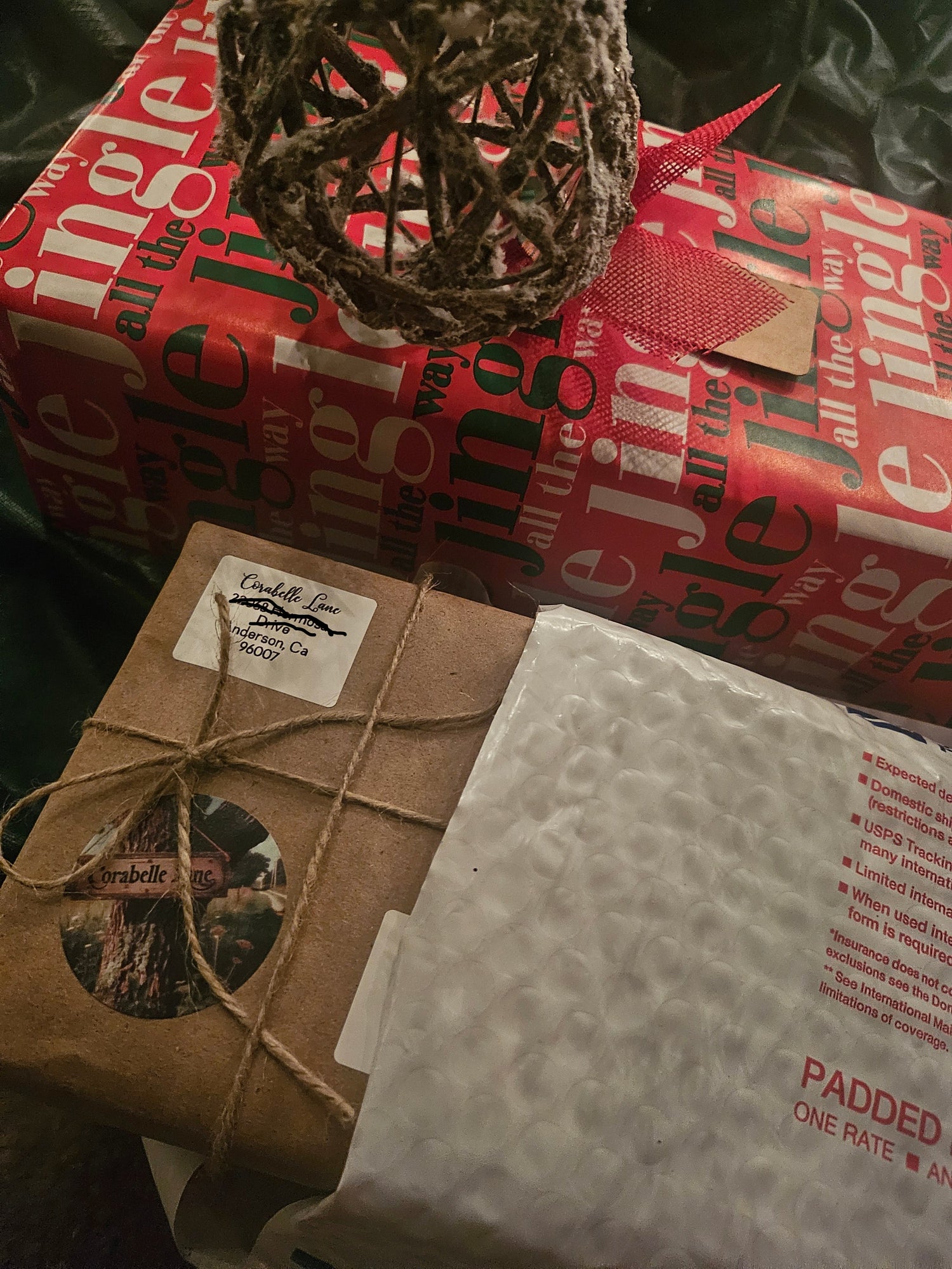 Packaged items including a red box, brown paper package with string, and bubble wrap on a dark surface.
